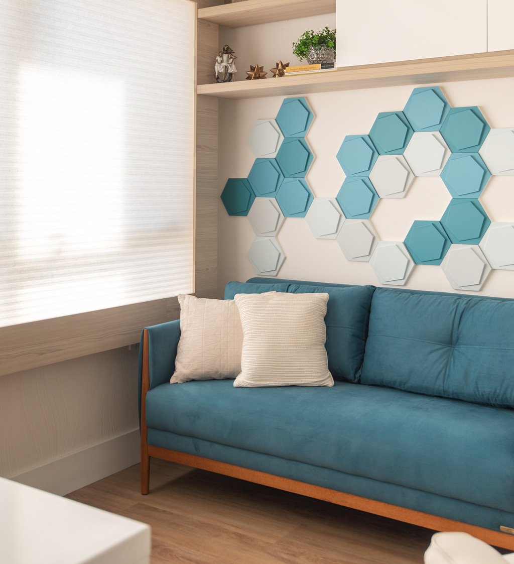 Ambiente composto por um sofá azul turquesa. A parede do fundo com revestimento Jump nas cores cinza, e turquesa. 