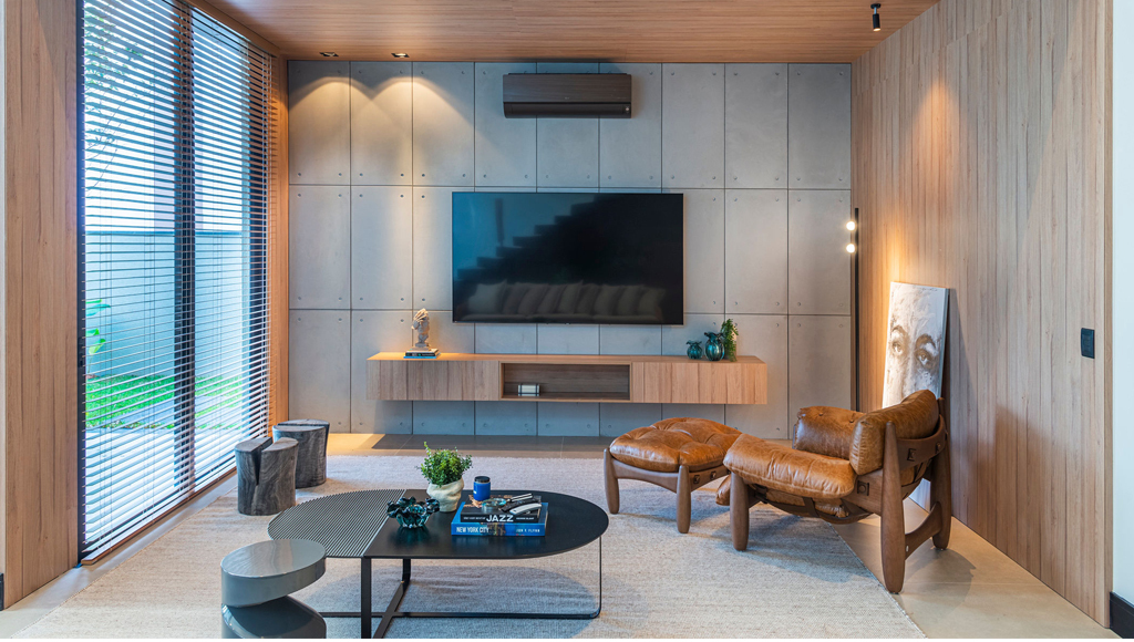 Sala de estar com revestimento novo urbano atrás da TV, móveis no estilo industrial.